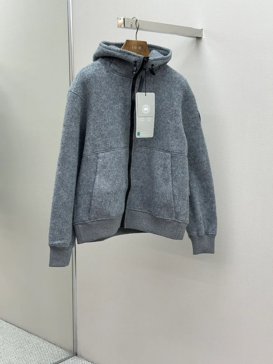 P800 ￼ Canada Goose Fleece Badge Hooded Jacket Fabric selection: Wool fleece fabric blended with wool as the main body and a very small amount of spandex and polyester fiber. Wool is a core natural ingredient that provides unparalleled temperature regulation, antibacterial and anti-odor properties and a skin-friendly feel. The feeding of a small amount of spandex gives the fabric a certain degree of four-way elasticity, making it non-restrictive during daily activities. As the basis of fleece's structure, polyester fiber enhances the fabric's durability, wrinkle resistance and quick-drying properties. It contributes to the loft of the fleece and provides functions such as trapping air.  Detail 1: The sleeves and hem are closed with 2×2 ribbing. Its strong elasticity can closely fit wrists and waists of different thicknesses, forming an effective 'seal' to prevent cold wind from blowing back. It can still maintain its original shape after repeated stretching and use, and is not easy to loose and deform. And the ribbed cuffs can convey a sense of design and enhance the visual beauty.  Detail 2: The combination of hood design and elastic buckle improves warmth and windproof performance when wearing.  Accessories: Customized elastic drawstring buckle Customized zipper pendant Customized armband SIZE: S M L XL